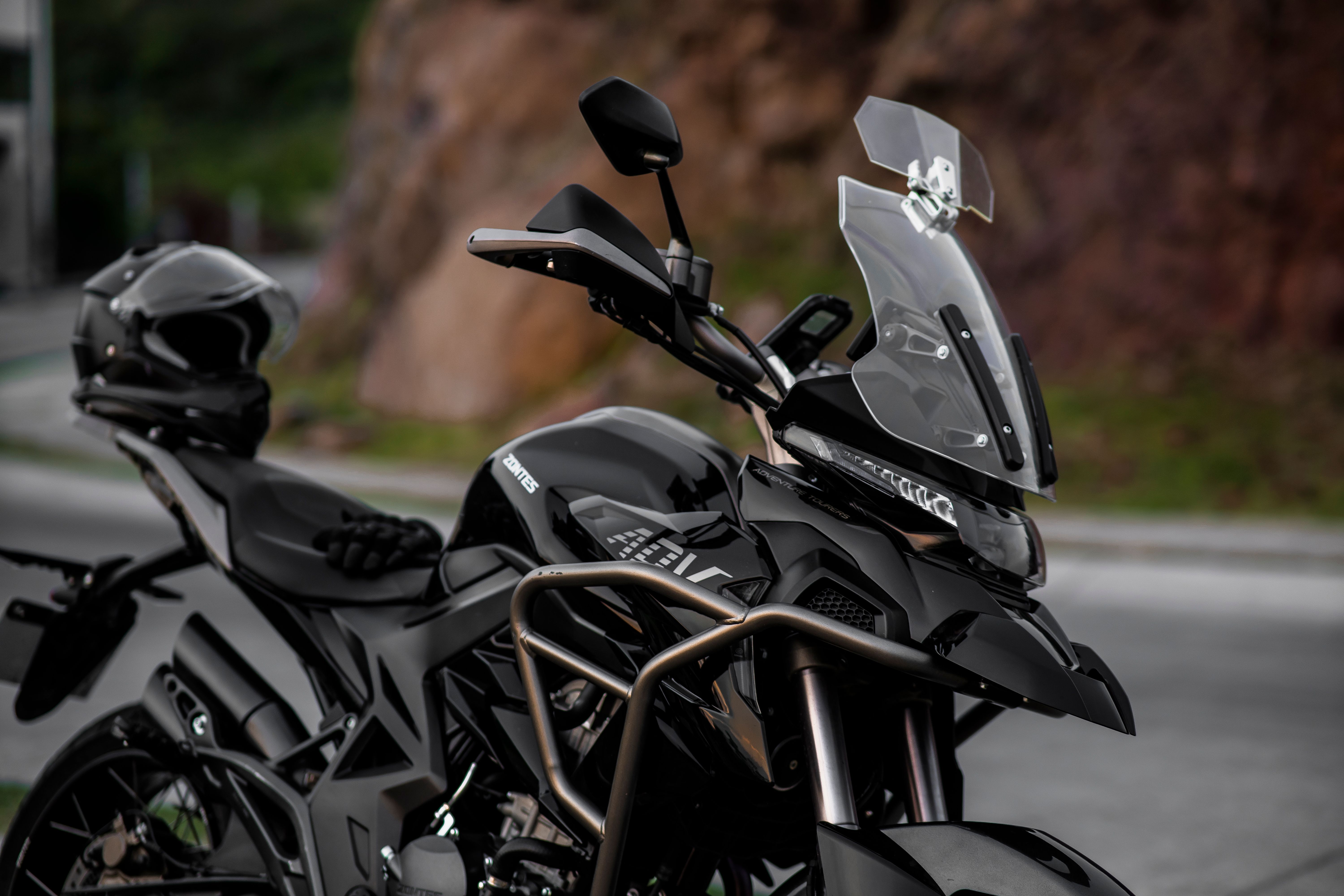Close-up of a parked black adventure motorcycle with a clear windscreen outdoors