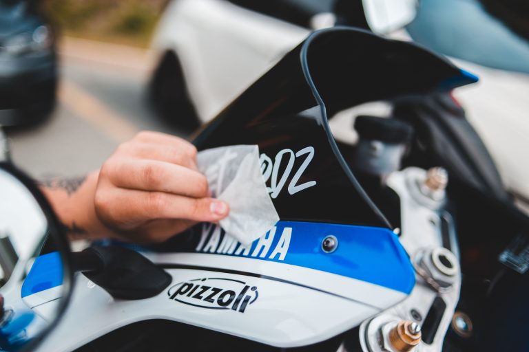 Rider using a soft cloth to wipe and clean the multi-colored windscreen of a chopper motorcycle