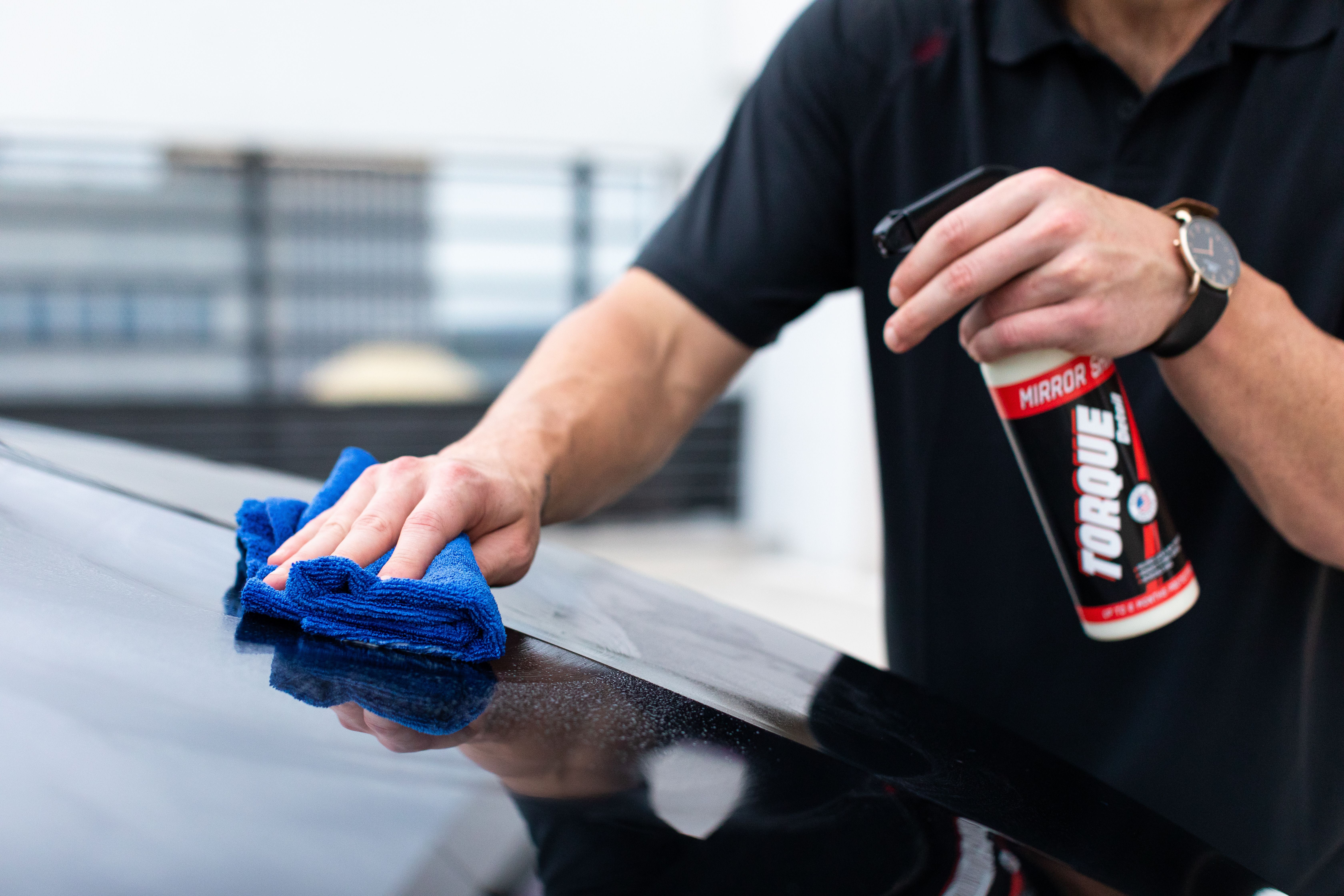 Hands cleaning a surface with a microfiber cloth and spray cleaner for a streak-free finish