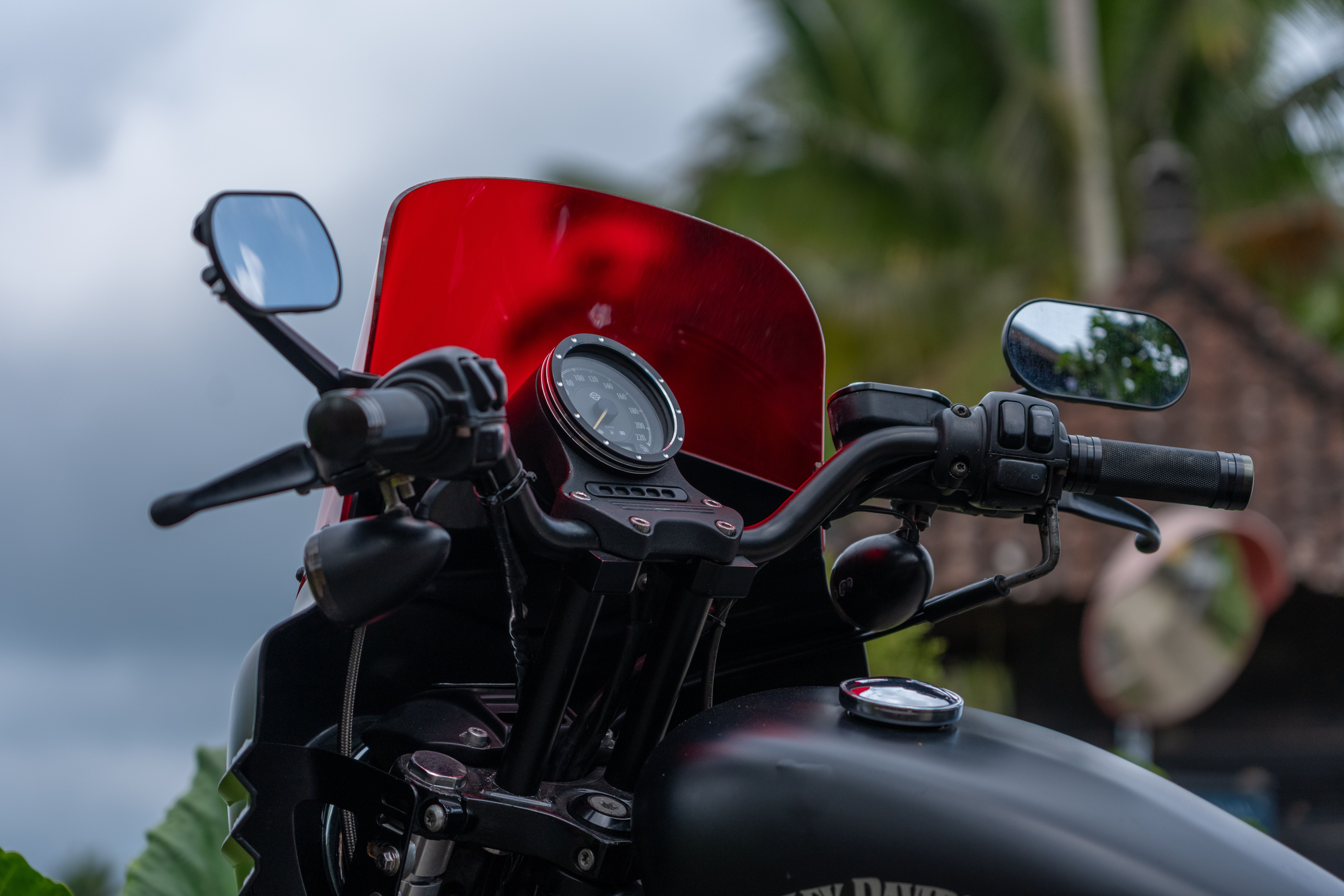 Close-up of motorcycle handlebars and red windscreen