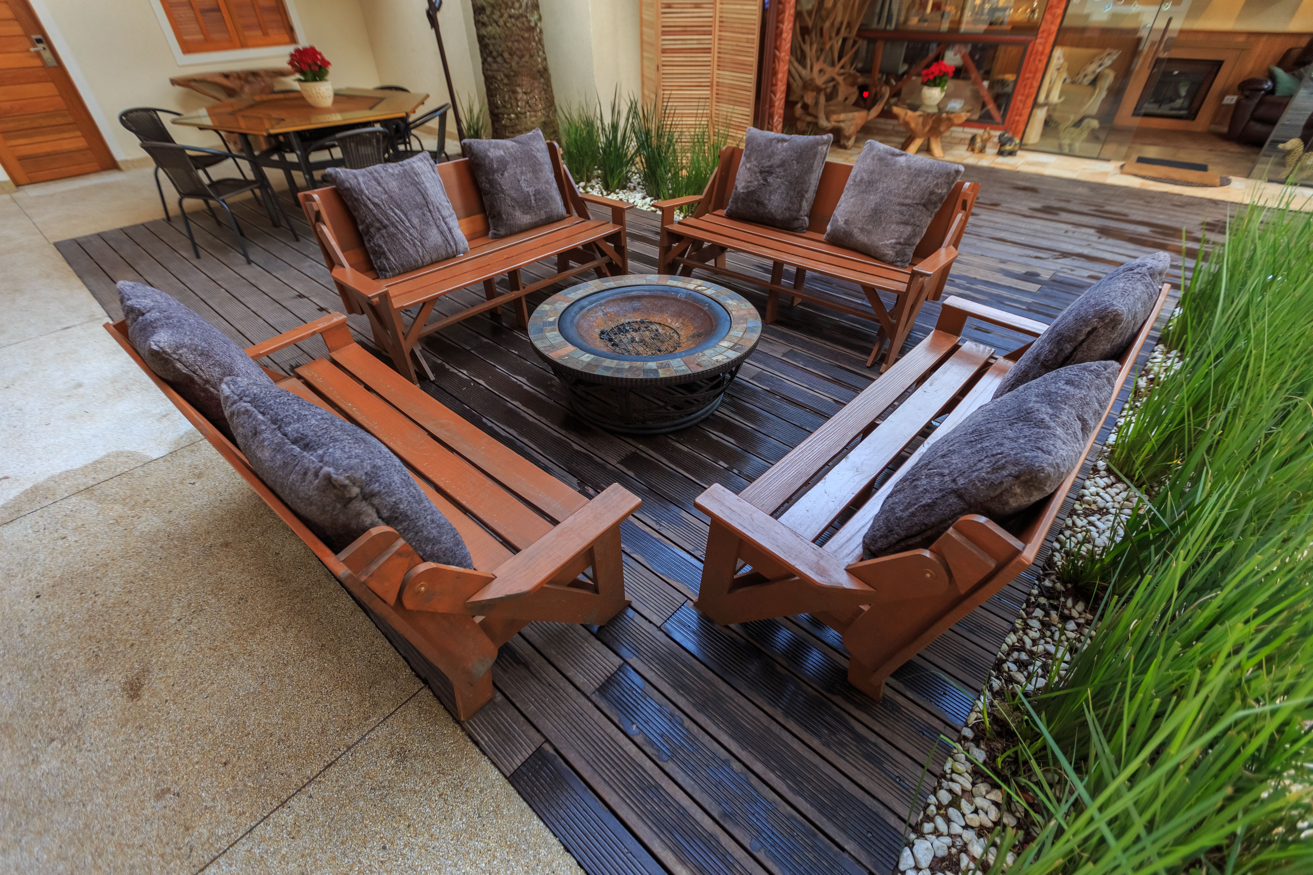 Inviting backyard lounge with wooden benches and a central fire pit, designed for comfortable outdoor gatherings.