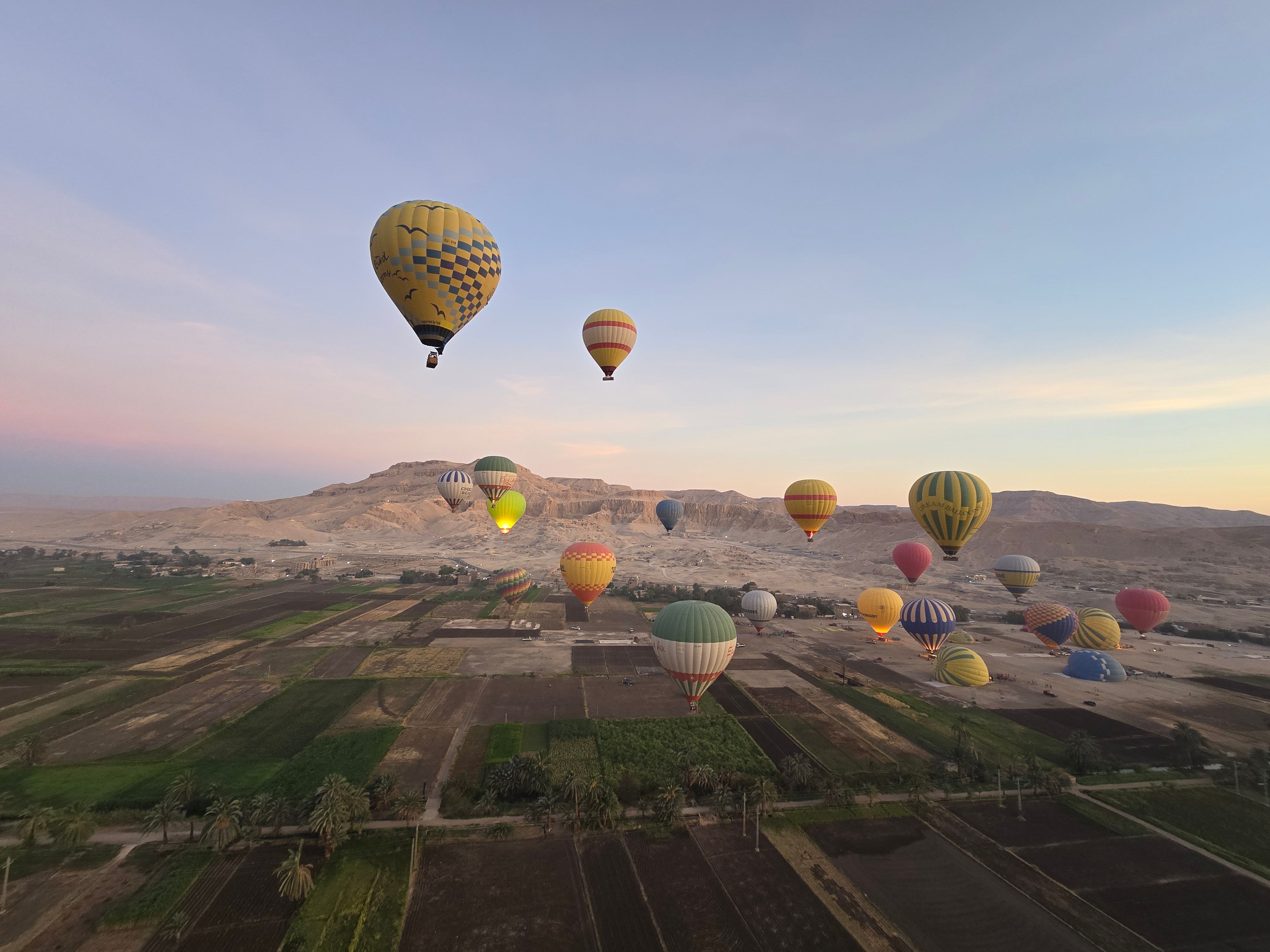 Colorful hot air balloons rising over the Luxor desert landscape at sunrise