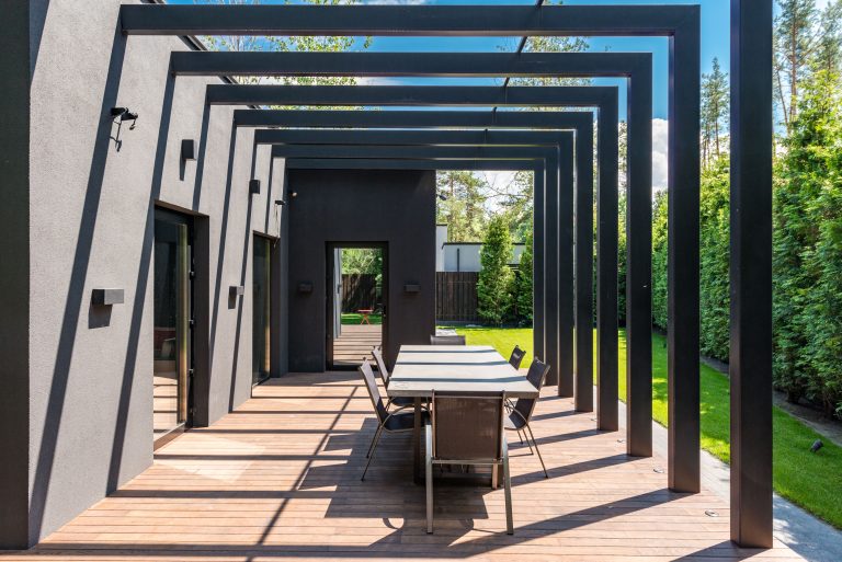 Contemporary backyard patio with a pergola and outdoor dining set, showing a modern design for comfortable entertaining.