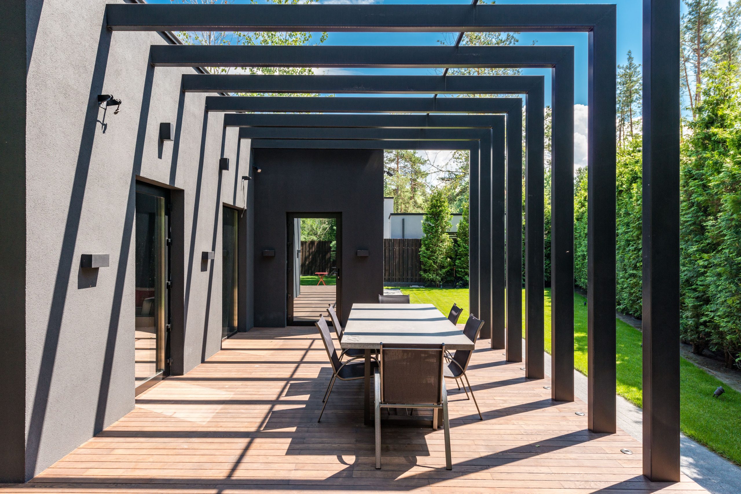 Contemporary backyard patio with a pergola and outdoor dining set, showing a modern design for comfortable entertaining.