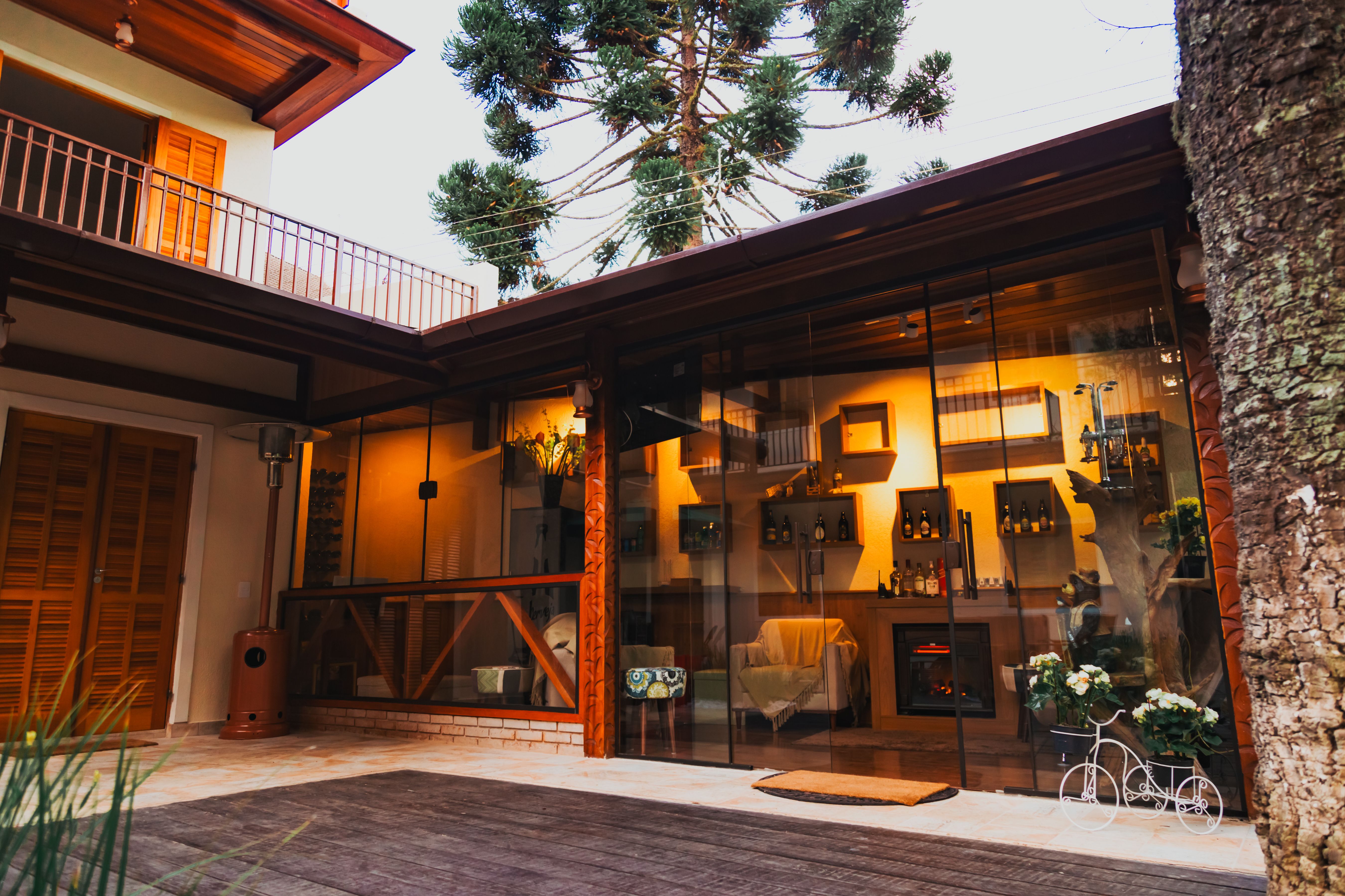 Modern home with a glass wall opening onto a cozy patio, illustrating seamless indoor-outdoor backyard design.