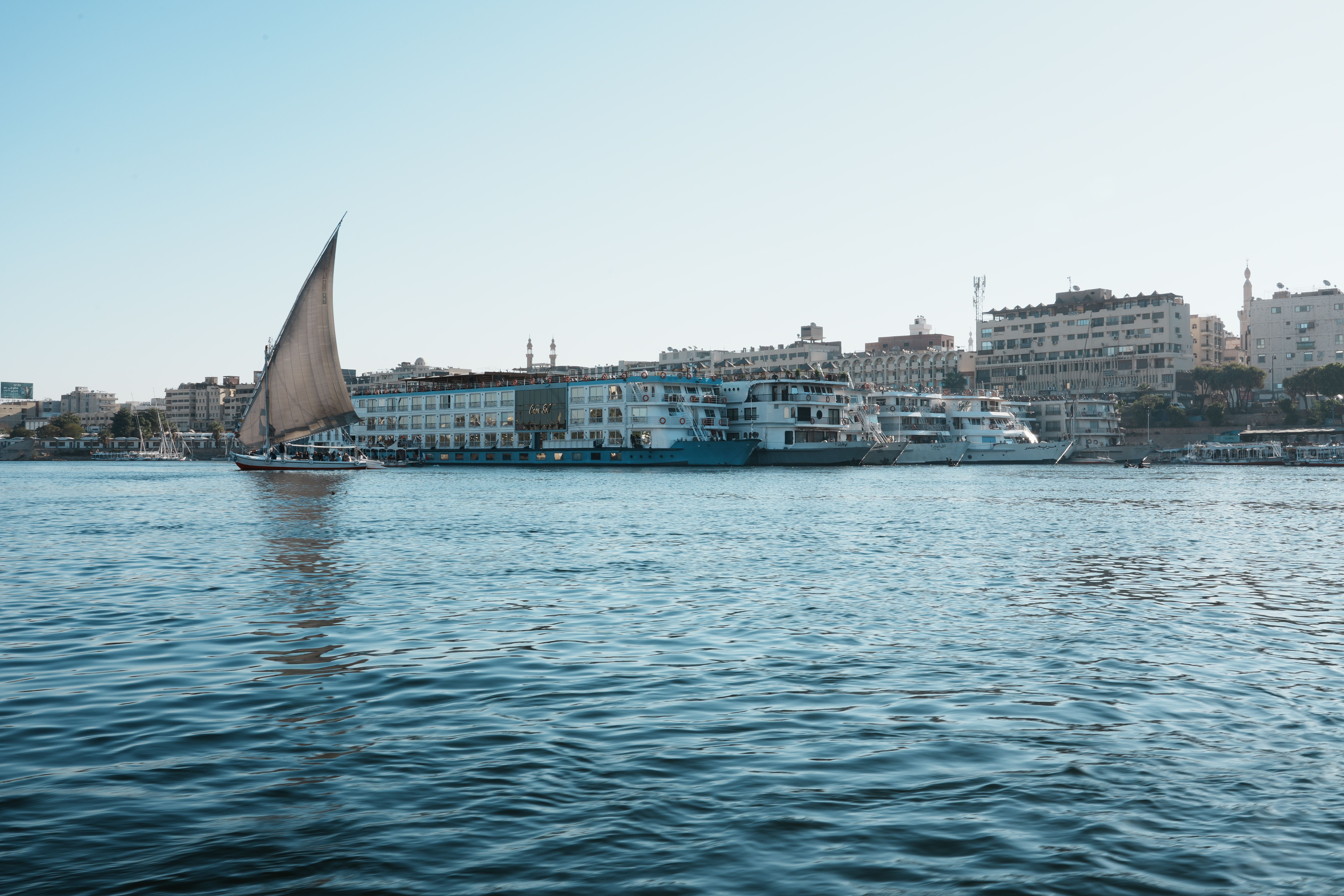 Traditional felucca sailboat on the Nile River near a city waterfront in Egypt